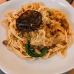 Creamy lemon ricotta pasta garnished with fresh basil and cracked black pepper in a white bowl